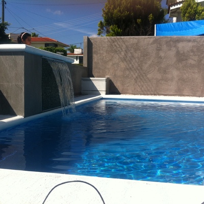 ALBERCA CON CASCADA A TRAVEZ DE UN PEQUEÑO MURO.